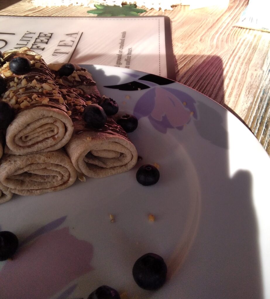 crepes arrtlate farcite con marmellata di arance e guarnite con crema al cacao granella di nocciole e mirtilli